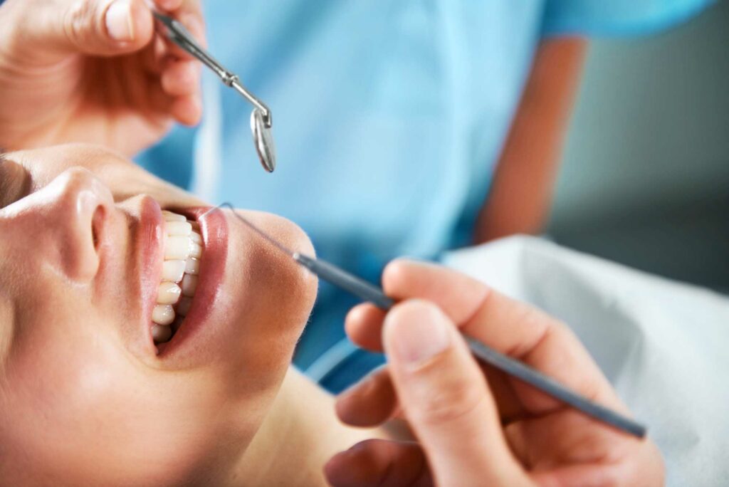 A close up view of a dentist using tools for a dental checkup on a female patient.